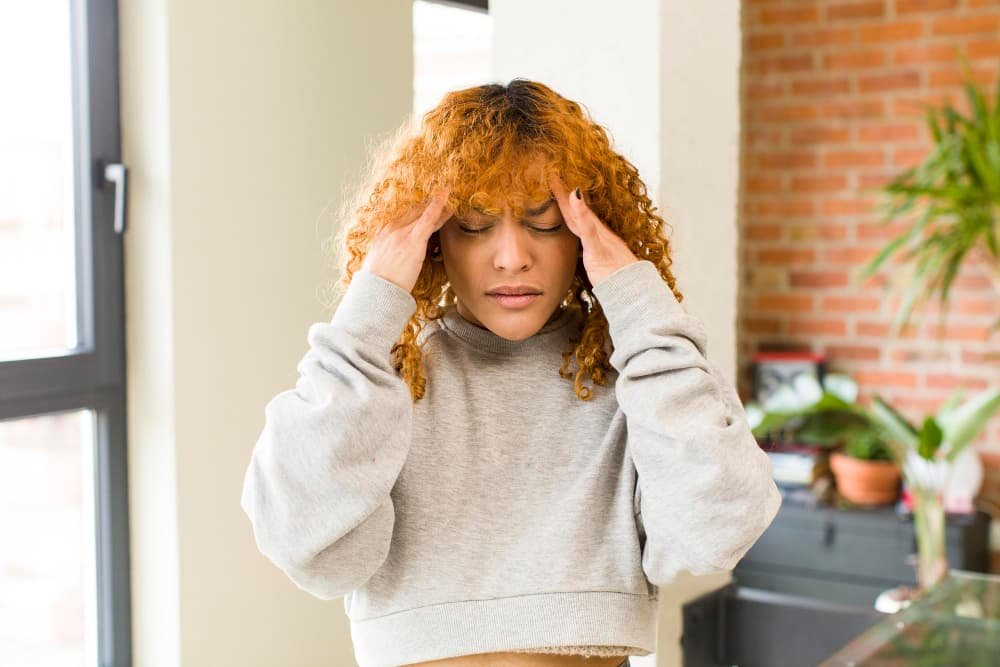 Jeune jolie femme latine aux cheveux roux qui se tient la tete